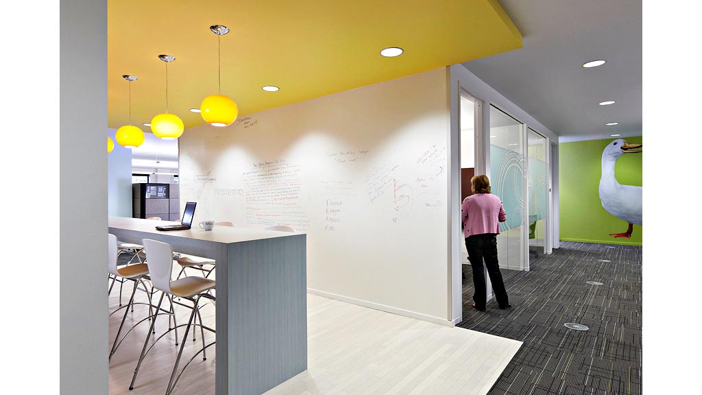 A person walking in a room with a table and chairs.