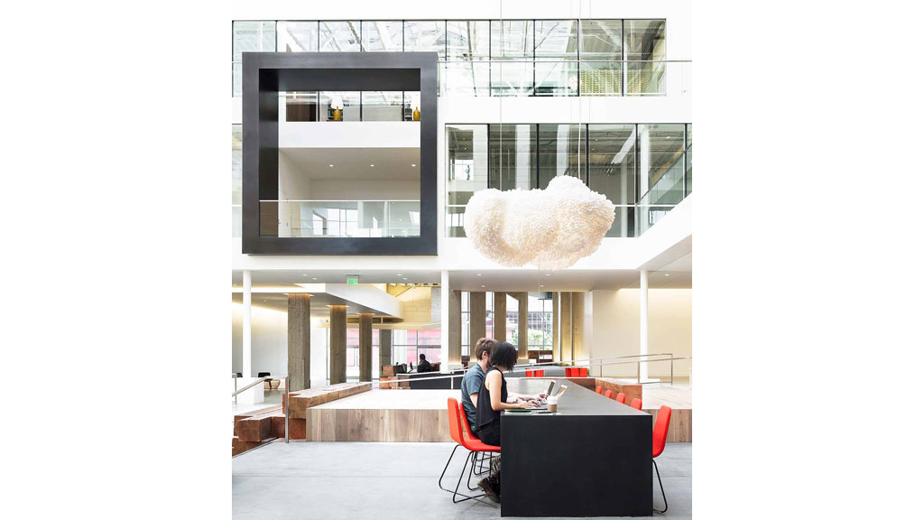 A person sitting at a table in a large room with a large white ball on the wall.