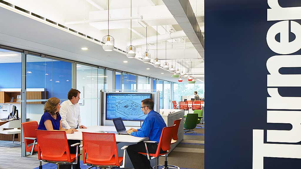 A group of people sitting at a table with laptops.