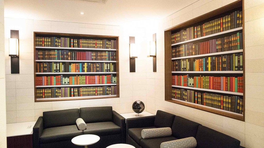 A room with a black couch and a bookcase with books.