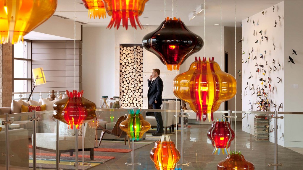 A person standing in a room with many lamps.