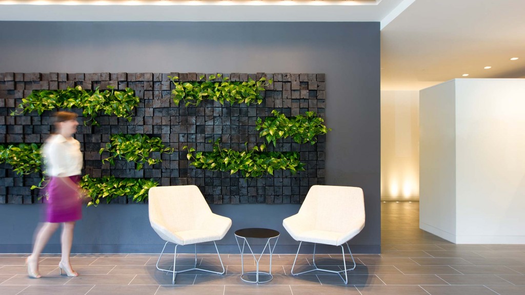 A person walking in a room with chairs and plants.