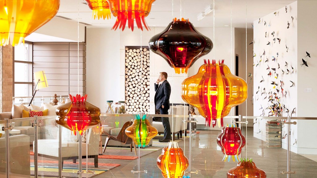 A person standing in a room with many lamps.