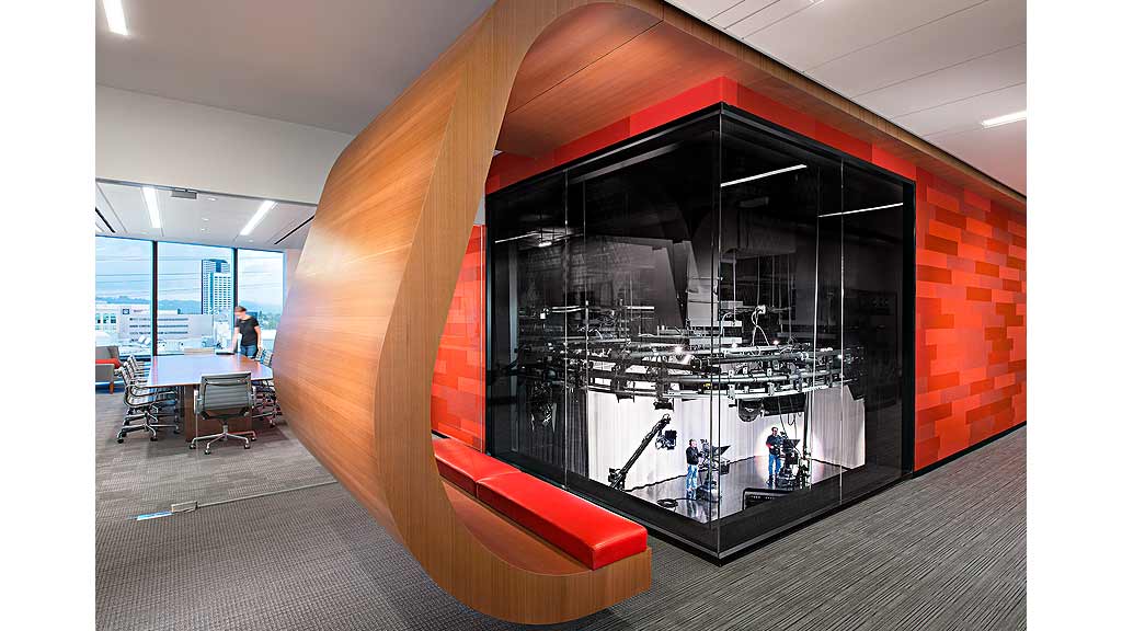 A large black object with a glass window in a room with a brick wall and a table and.