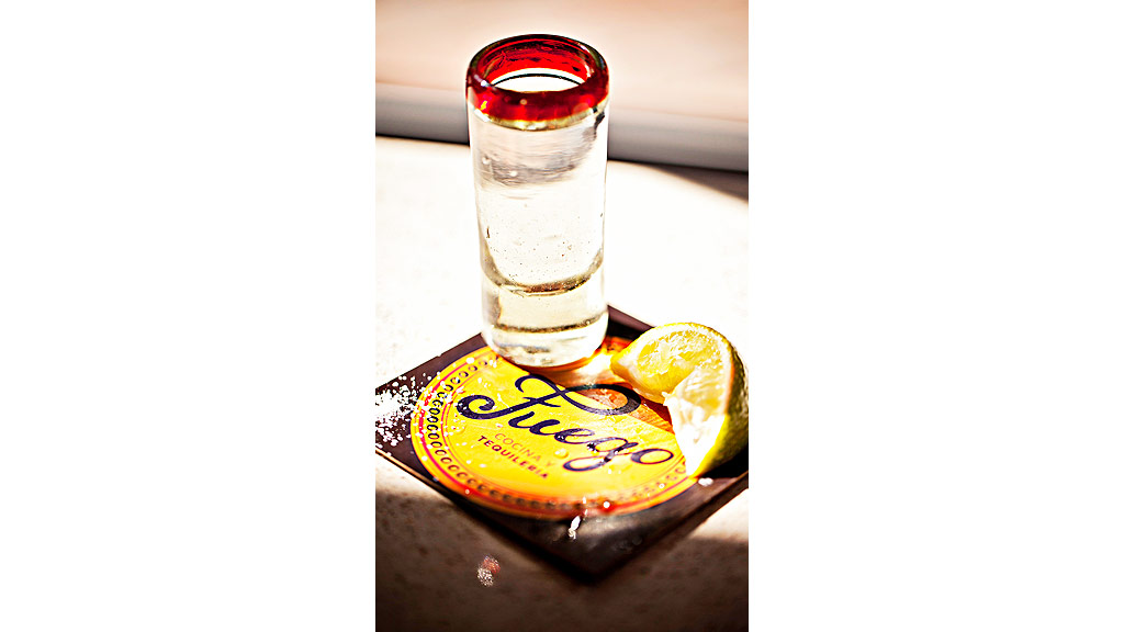 A glass of water and a bottle of alcohol on a table.