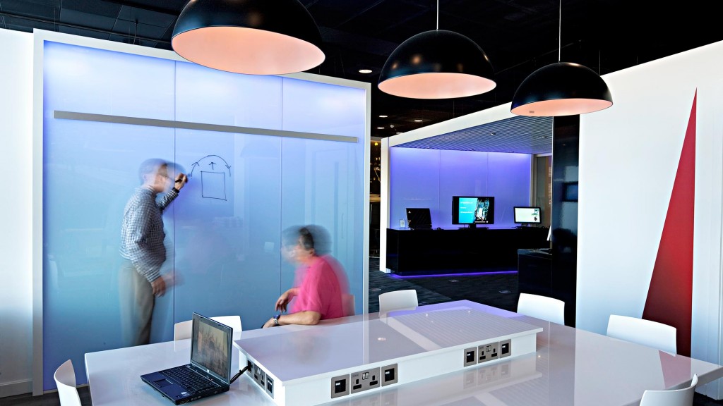 A man and woman in a room with a large screen and a woman.