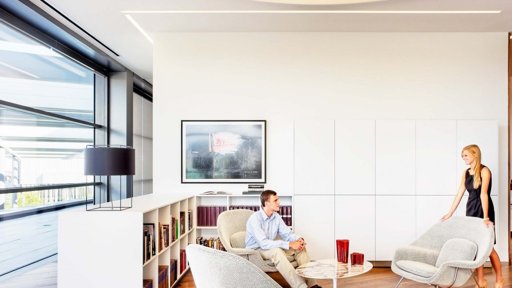 A woman standing next to a man sitting on a couch.