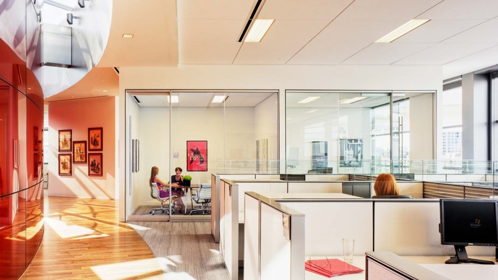 A couple of people sitting at a table in a large office.