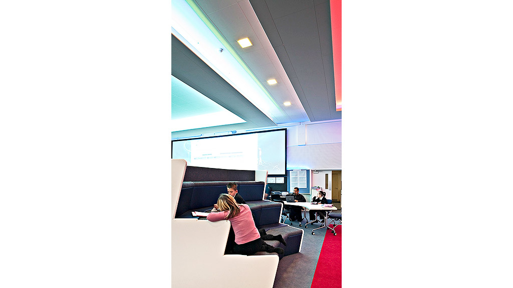 A group of people sitting at a table in front of a large screen.