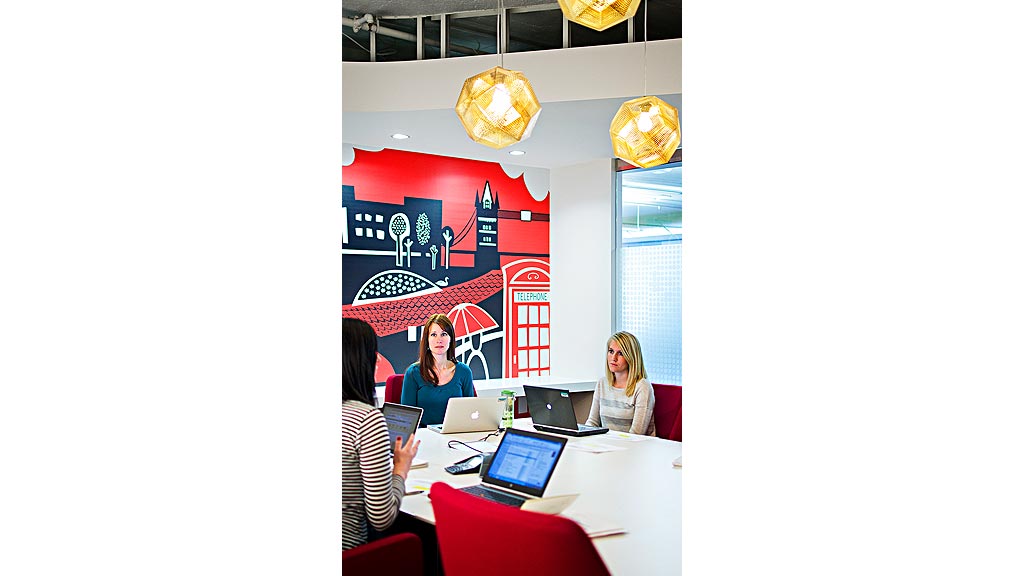 A group of women sitting at a table with laptops.