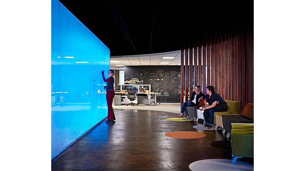 A person standing in a room with people sitting on chairs.