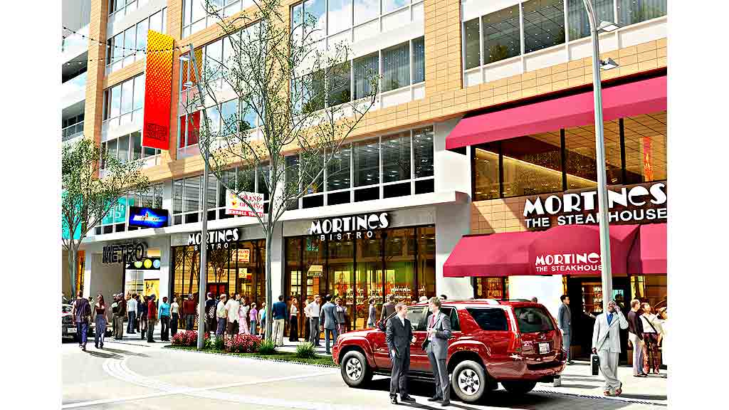 A red truck parked in front of a building with people walking around.