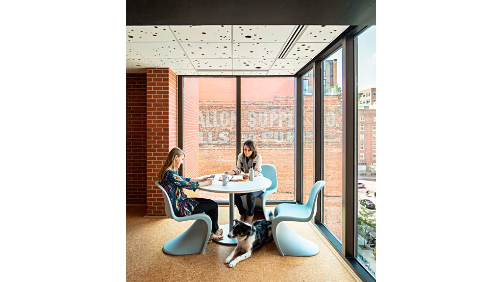 A couple of women sitting at a table with a dog.