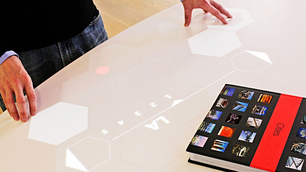 A person's hands on a table with a tablet and a tablet.