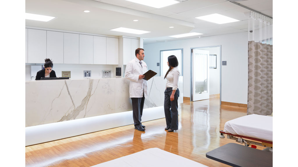 A man and a woman in a room with a whiteboard and a woman standing in the front.