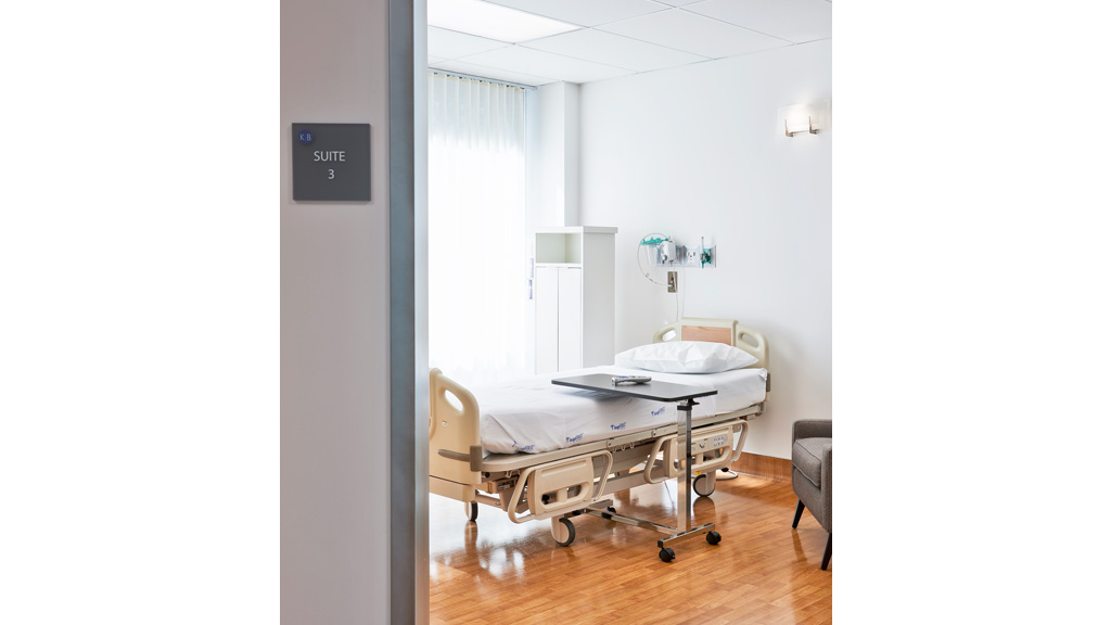 A hospital room with a bed and a chair.