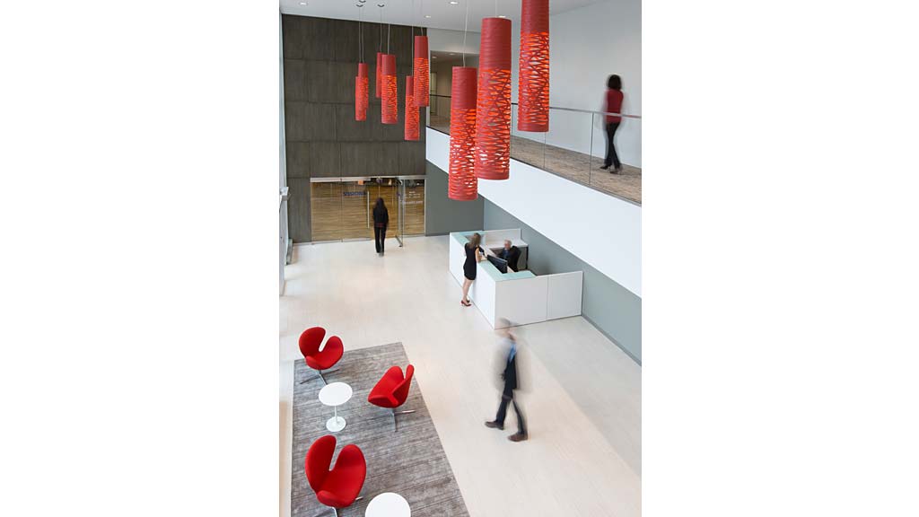 A group of people in a room with red chairs and a table.