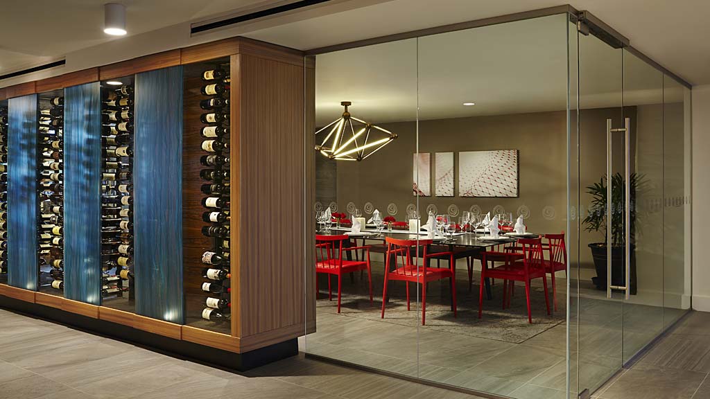 A room with a glass wall and a table with chairs and a light.