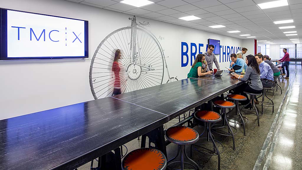 A group of people sitting at a table with a large fan.