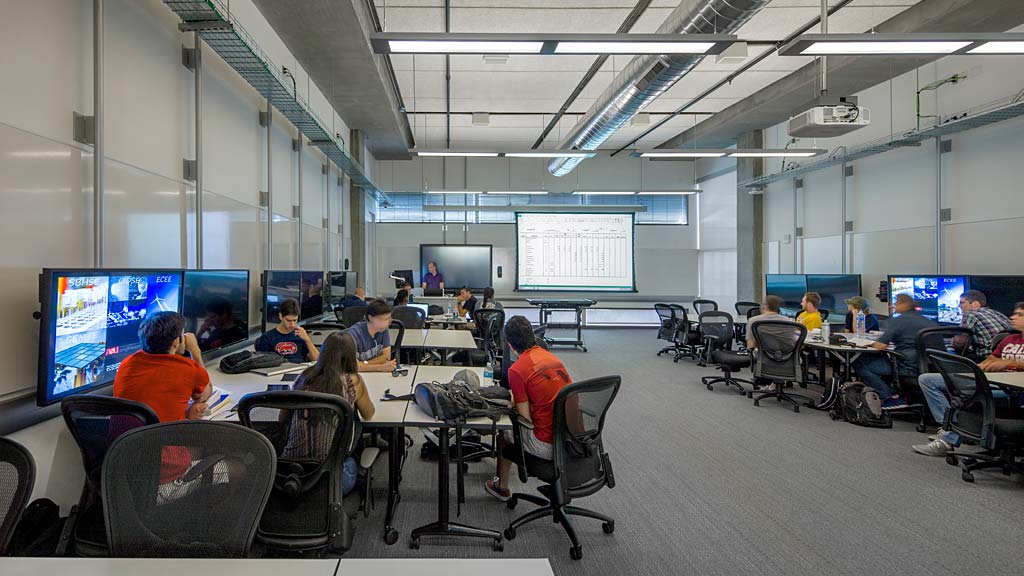 A group of people sitting around a table with computers.