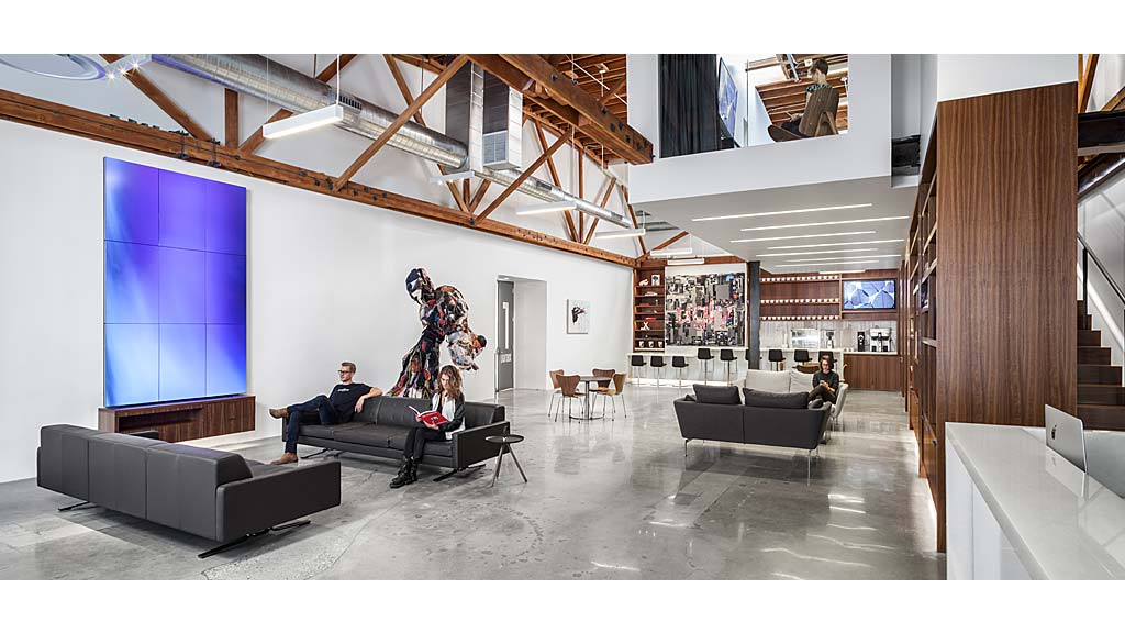 A group of people sitting on a couch in a room with a wood ceiling.