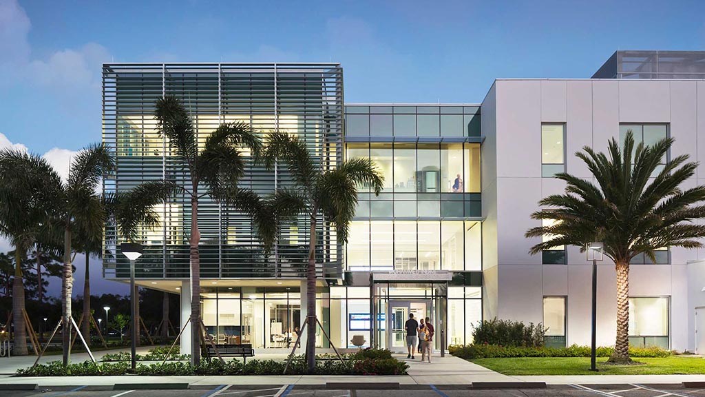 A building with palm trees in front.