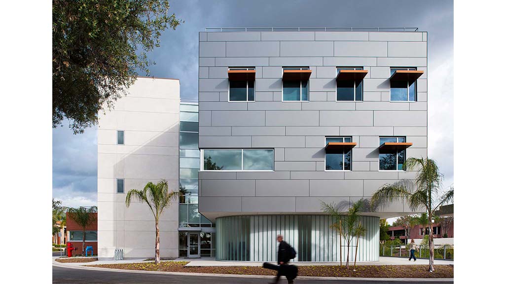 A person sitting on a bench in front of a building.