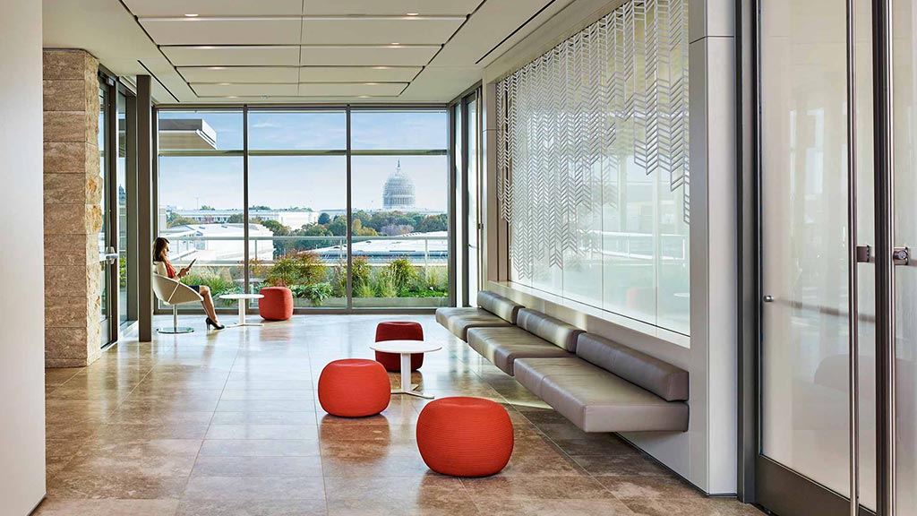 A room with a glass door and a person sitting on a bench.