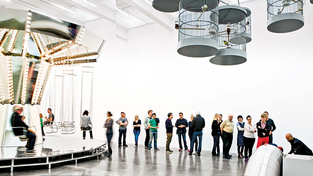 A group of people in a large room with white walls and a large white ceiling.