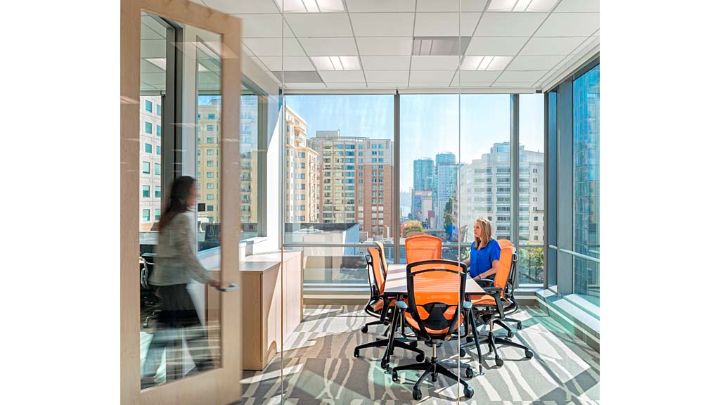 A person standing next to a person seated at a table.