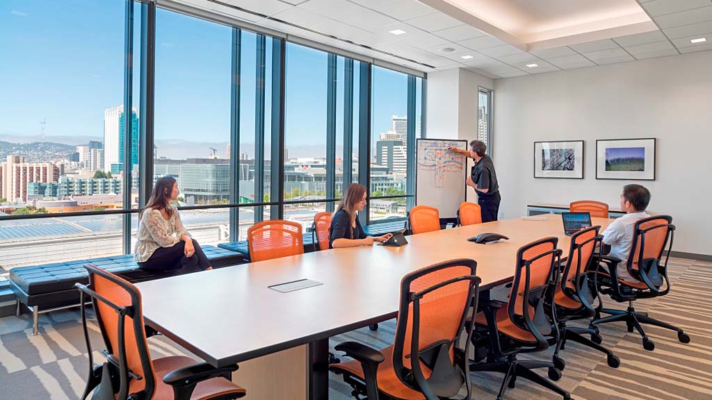 A group of people sitting around a table with a view of a city.