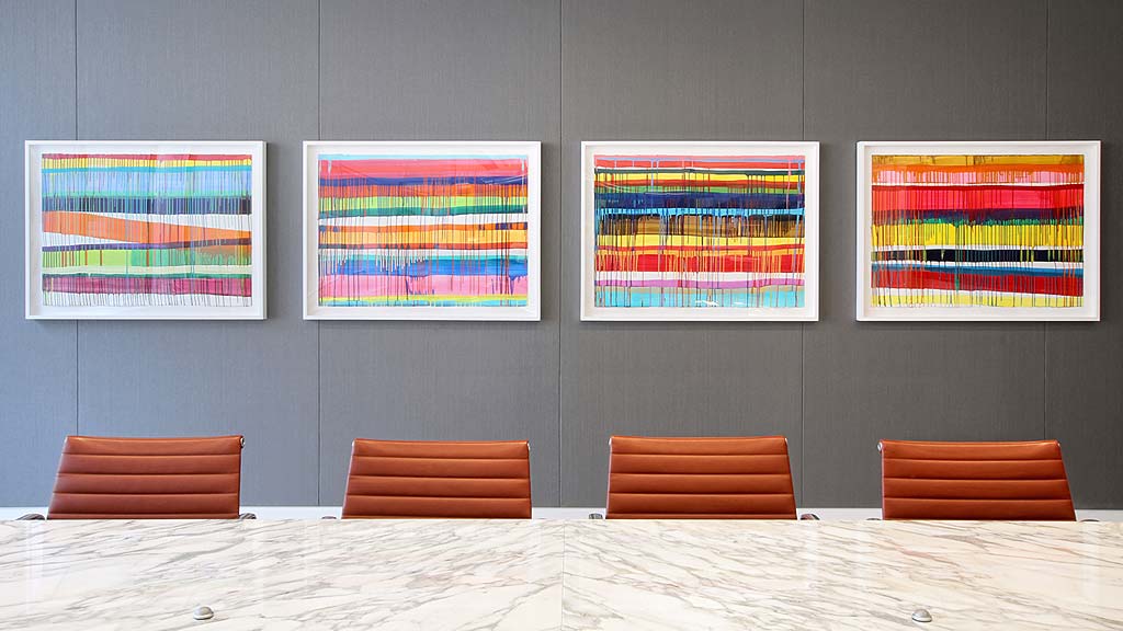 A group of chairs in front of a wall with colorful paintings.