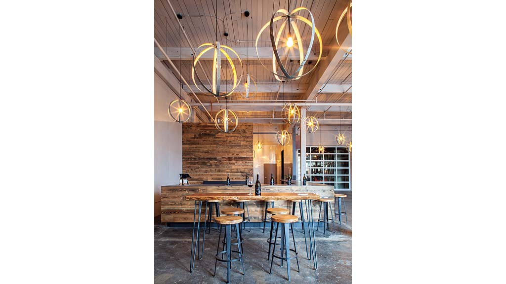 A bar with a chandelier and stools.