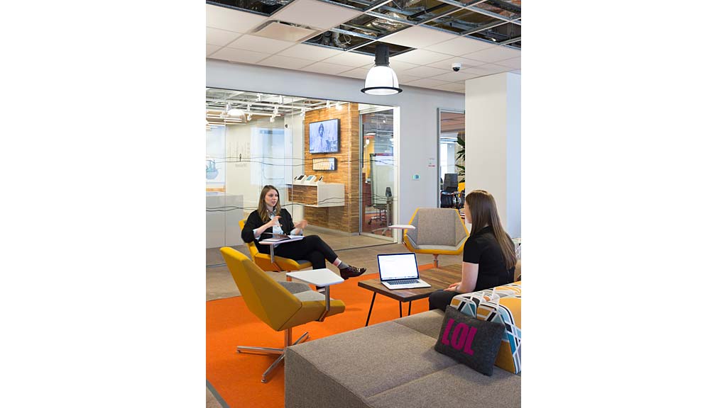 A couple of women sitting at a table with laptops.