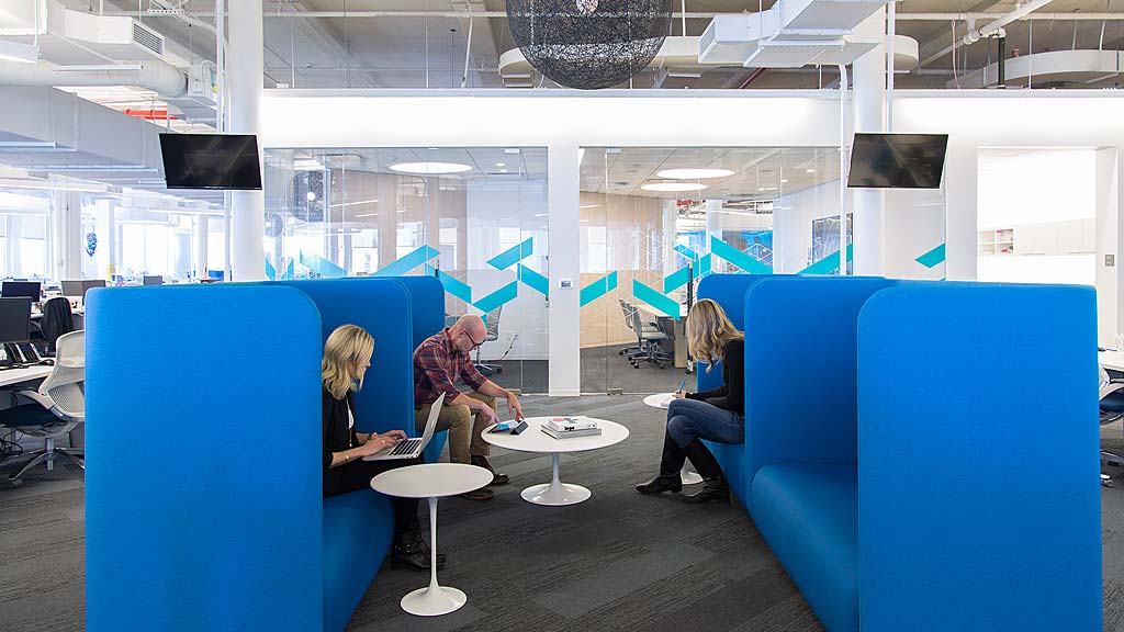 A group of people sitting in a room with blue couches.