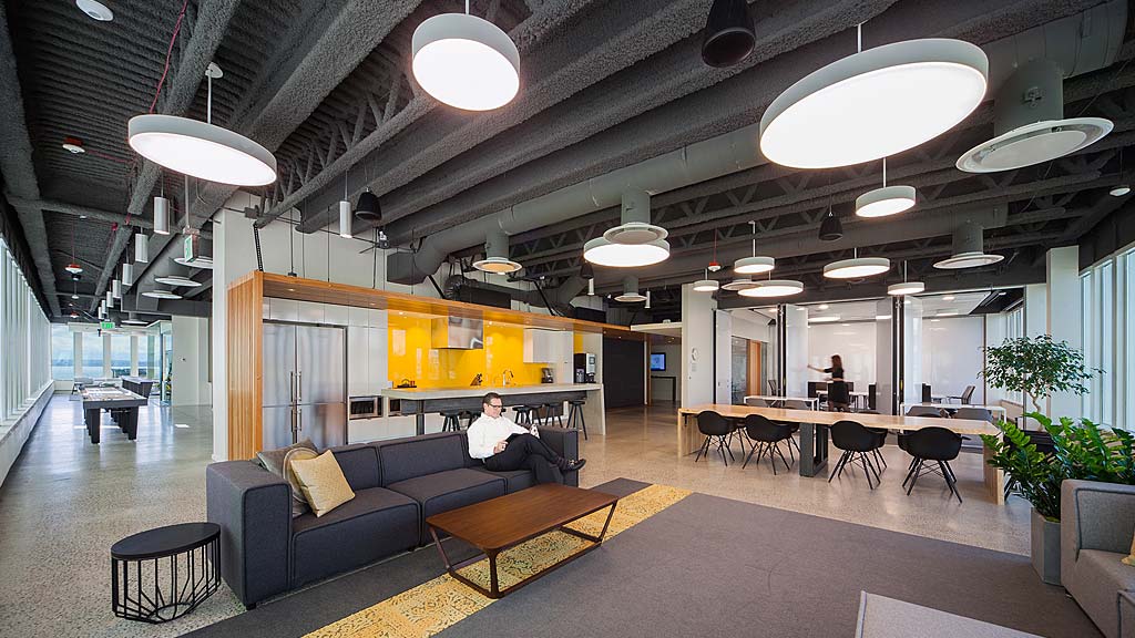 A person sitting in a room with a couch and tables.