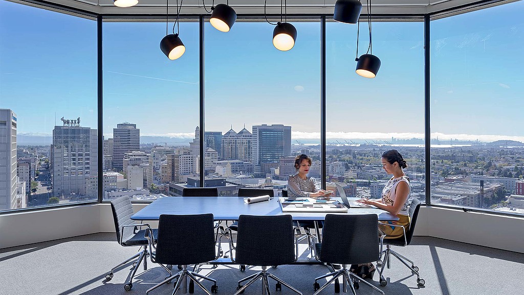 A couple of people sitting at a table with a view of a city.