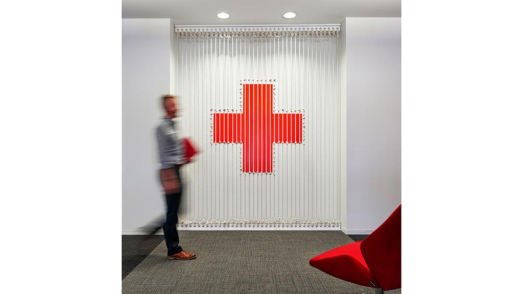 A person standing in front of a white wall with red and black letters.