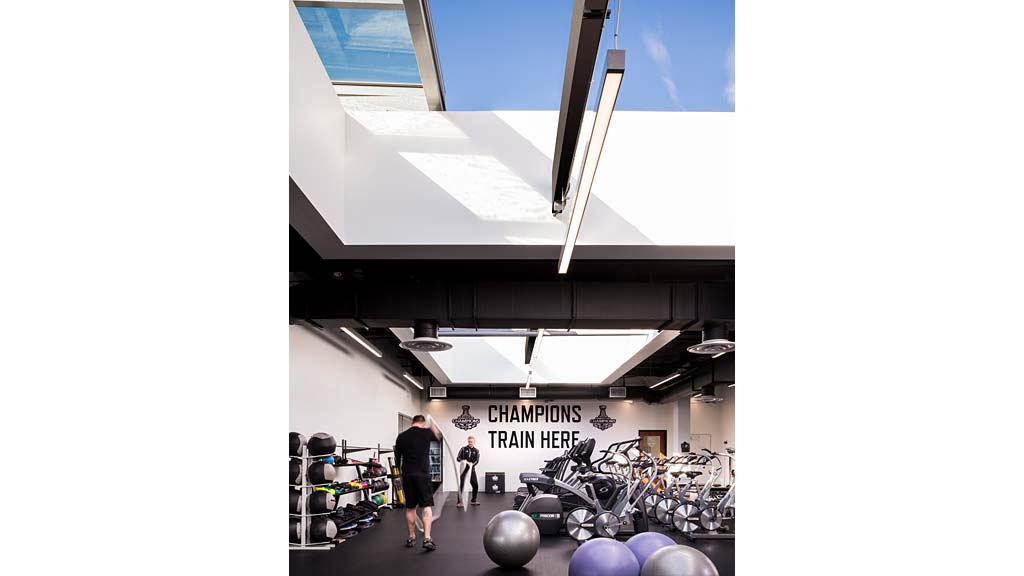 A man and woman standing in a room with a large display of motorcycles.