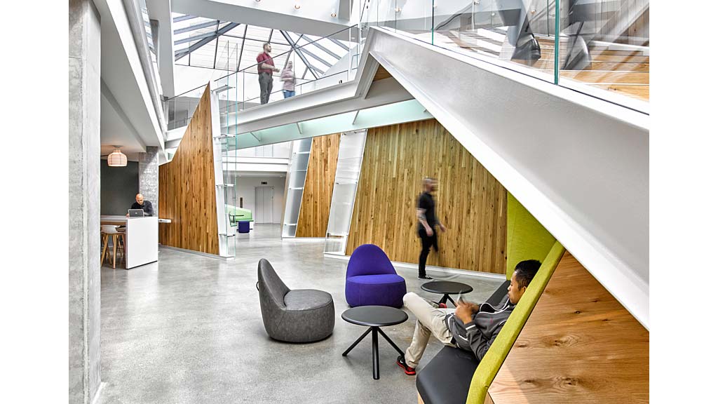 A person lying on a chair in a room with other people.
