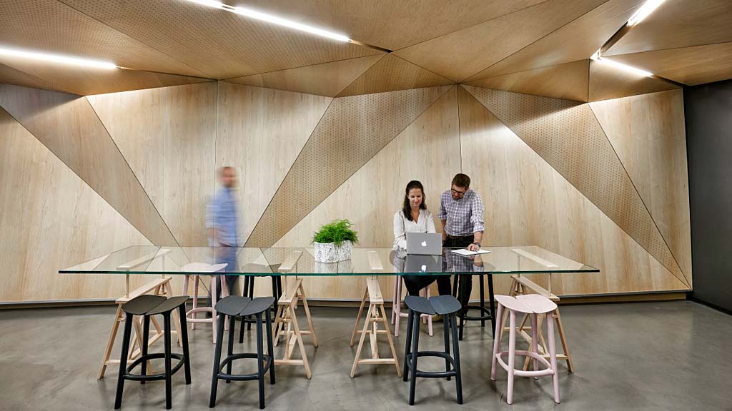 A group of people standing around a table with stools.
