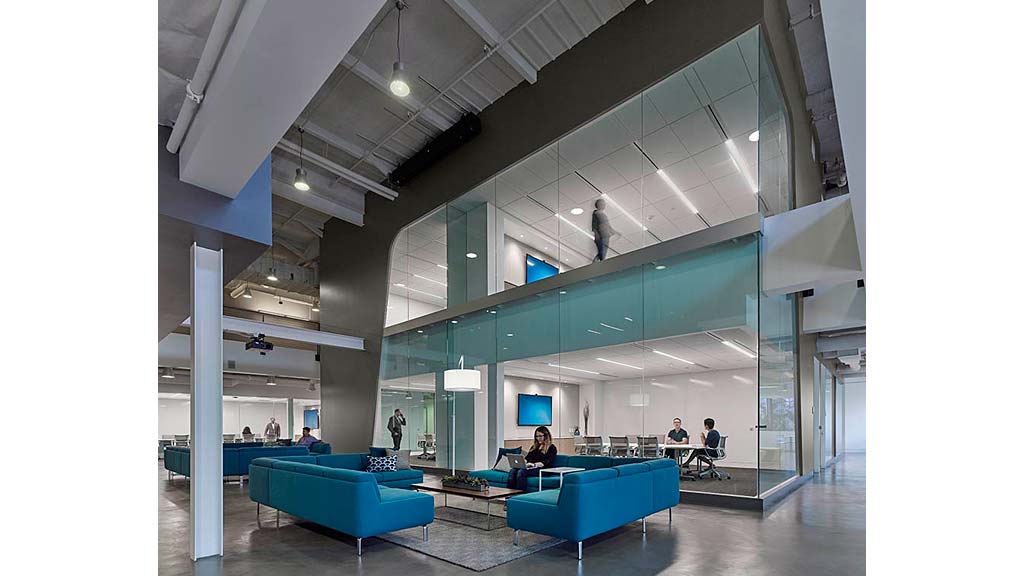 A group of people sitting on blue couches in a large room.
