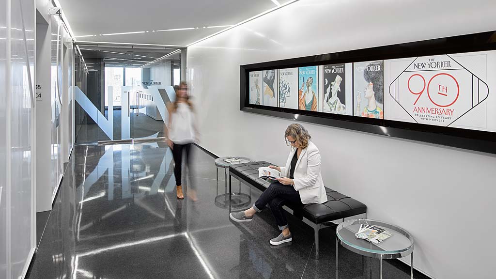 A person sitting on a bench in a room with a person standing.