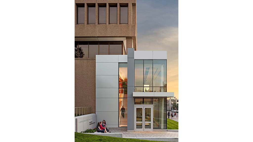 A couple of people sitting on a bench outside of a building.