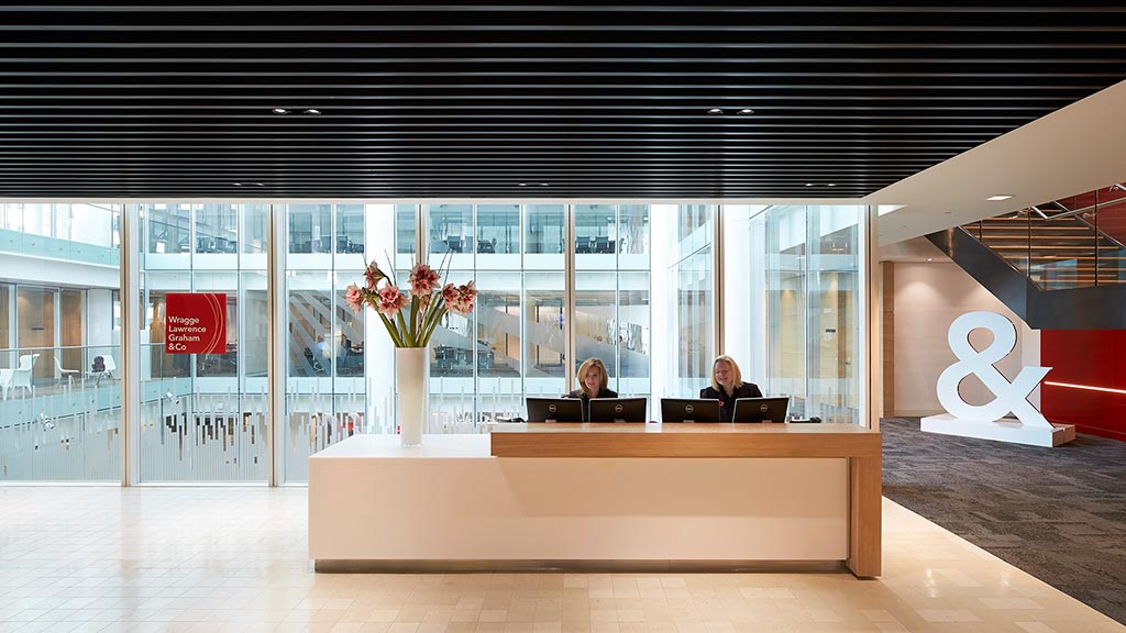 A couple of women sitting at a table in a large office.