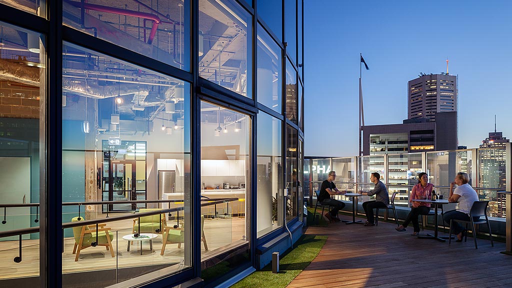 A group of people sitting on a bench in front of a building.