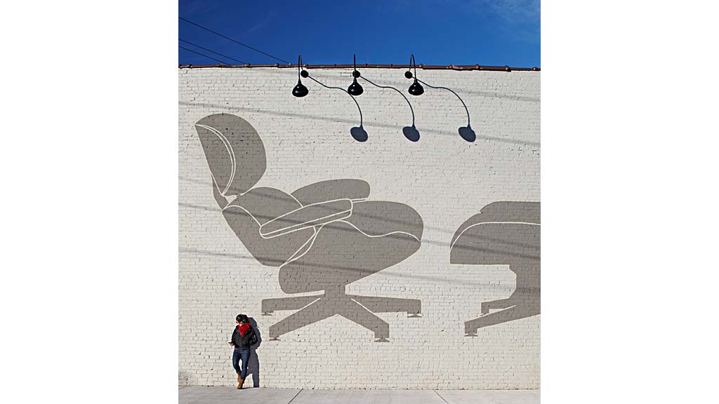 A person standing next to a wall with a drawing on it.