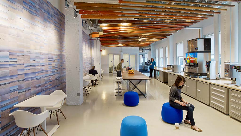 A person sitting in a chair in a room with people and tables.