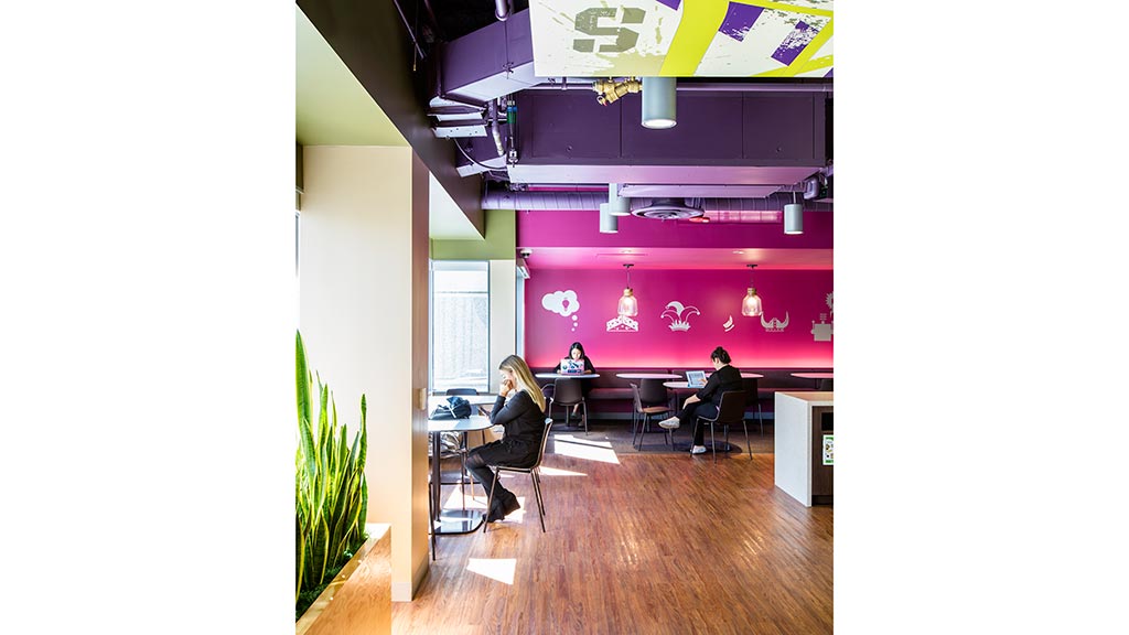 A group of people sitting at a table in a room with a large screen.