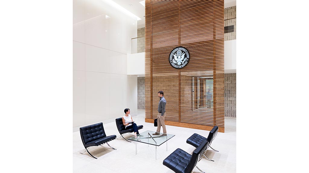 A man and a woman in a room with chairs and a large clock.